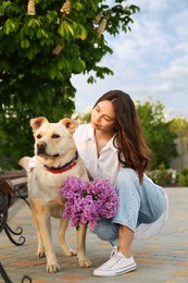 Photo of Woman with her pet and lilac flowers in park