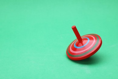 Photo of One bright spinning top on green background, space for text. Toy whirligig
