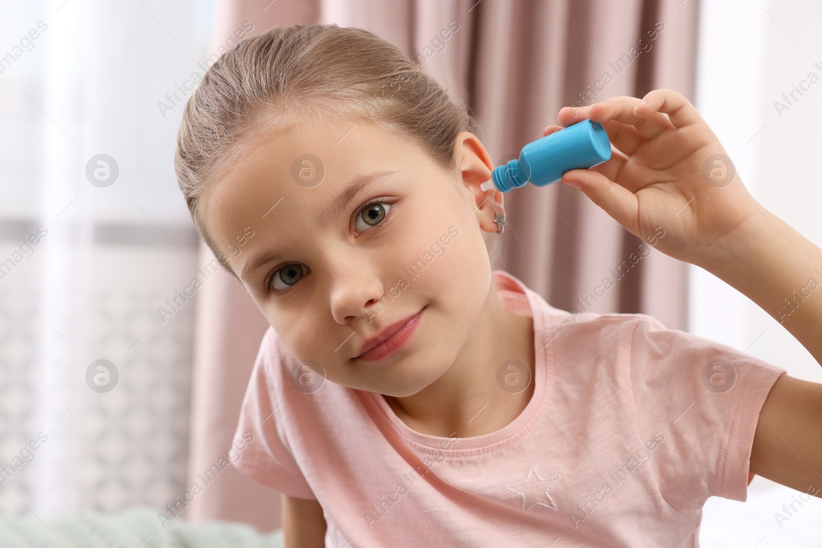 Photo of Little girl using ear drops at home