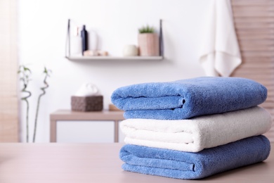 Stack of fresh towels on table in bathroom. Space for text