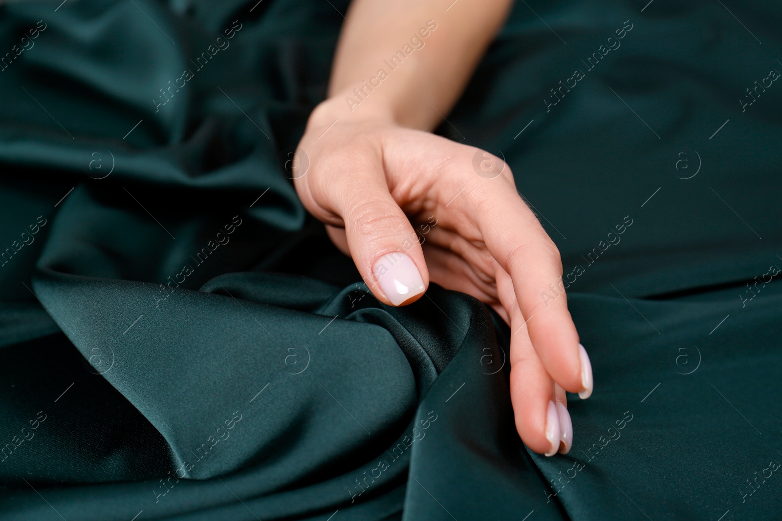 Photo of Woman touching soft dark green fabric, closeup