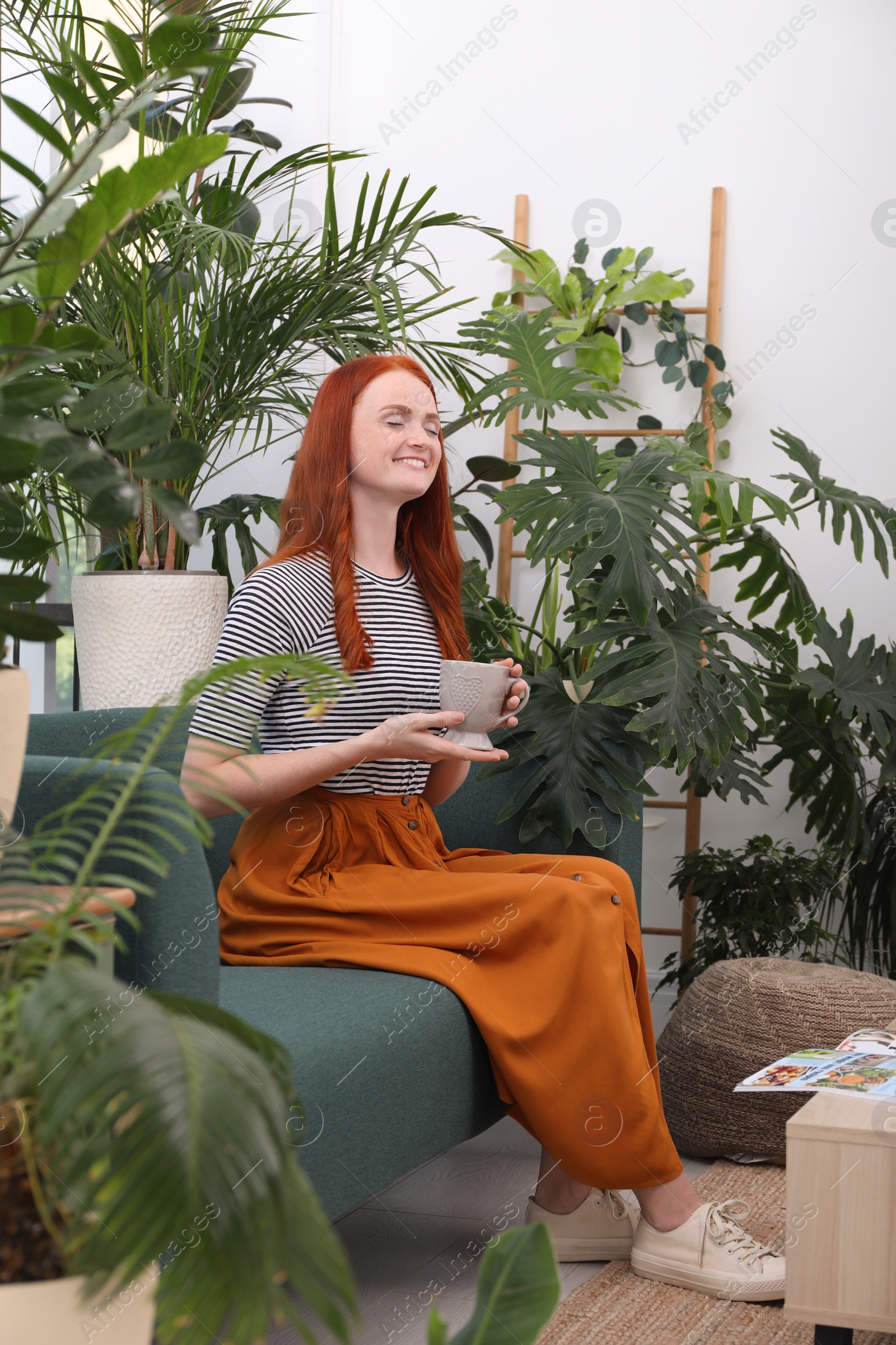 Photo of Beautiful woman with cup of tea resting on sofa in room