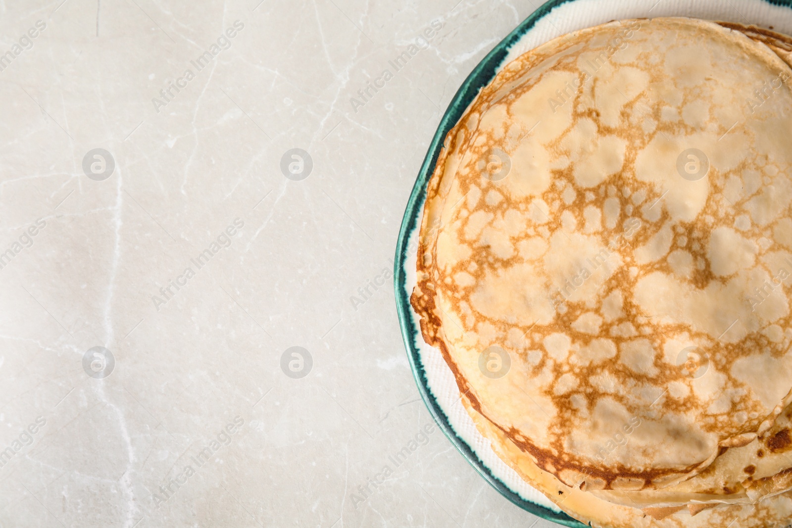 Photo of Stack of fresh thin pancakes on light grey marble table, top view. Space for text