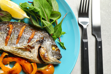 Delicious roasted fish with lemon on grey table, flat lay