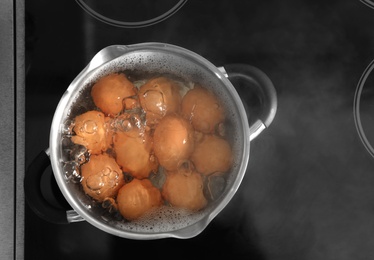 Cooking chicken eggs in pot on electric stove, top view. Space for text