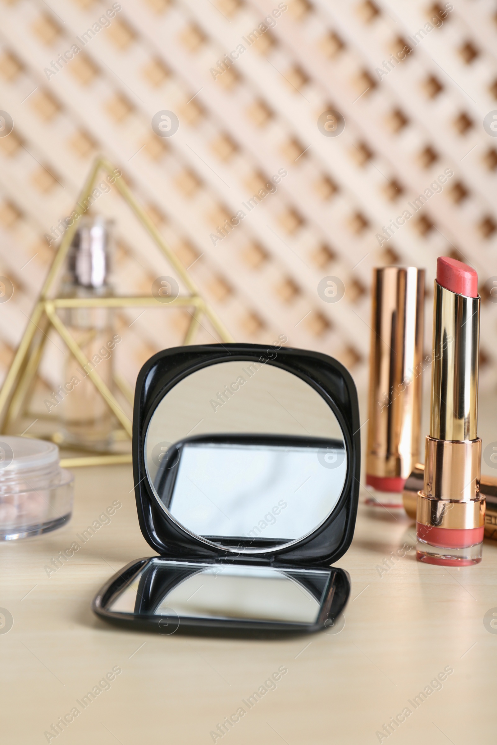 Photo of Stylish pocket mirror and cosmetic products on beige table