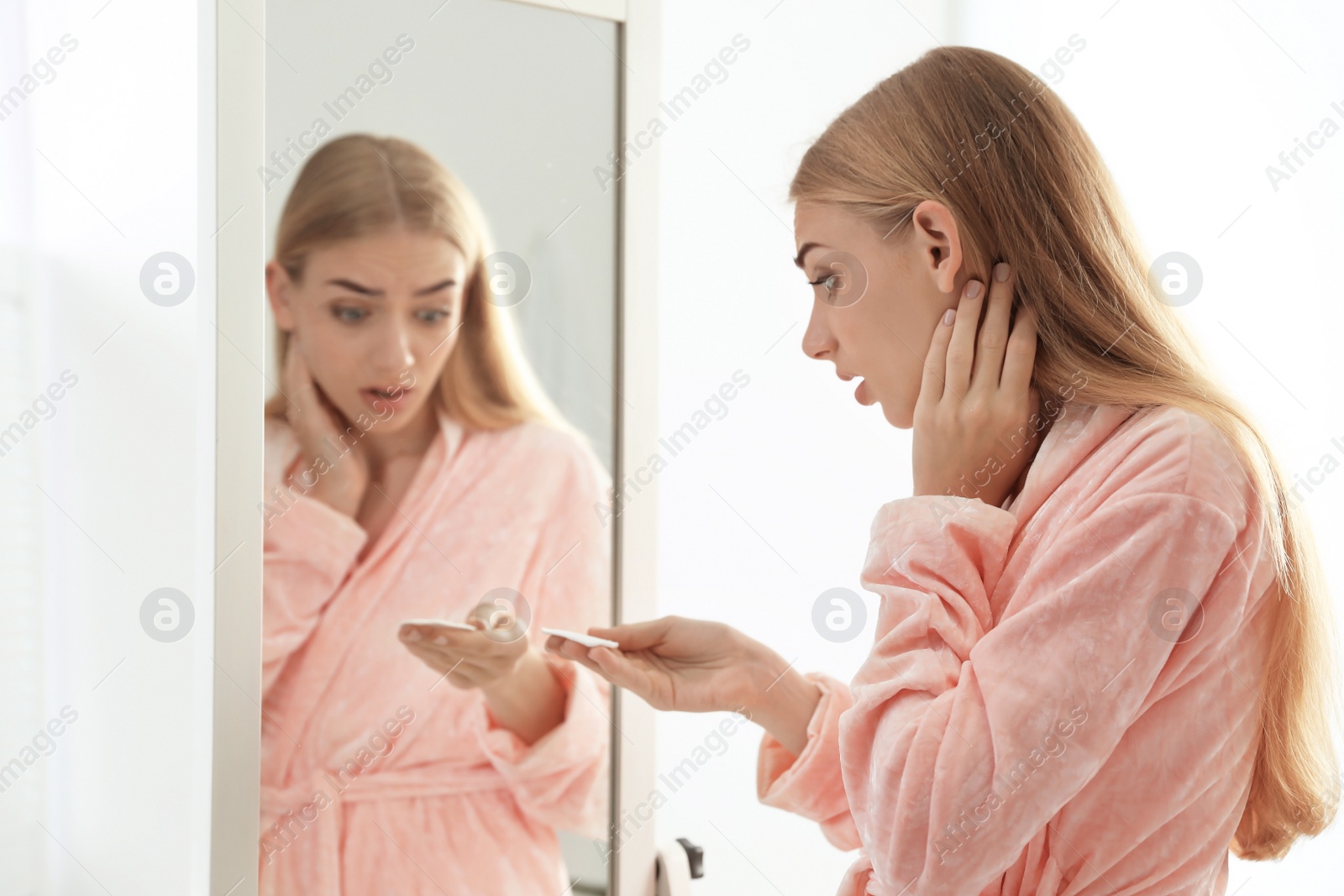 Photo of Young woman with eyelash loss problem near mirror indoors