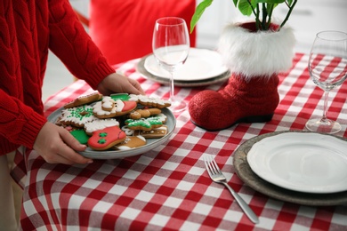 Photo of Woman with cookies setting table for Christmas dinner indoors, closeup