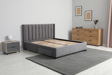 Photo of Comfortable bed with storage space for bedding under slatted base in stylish room