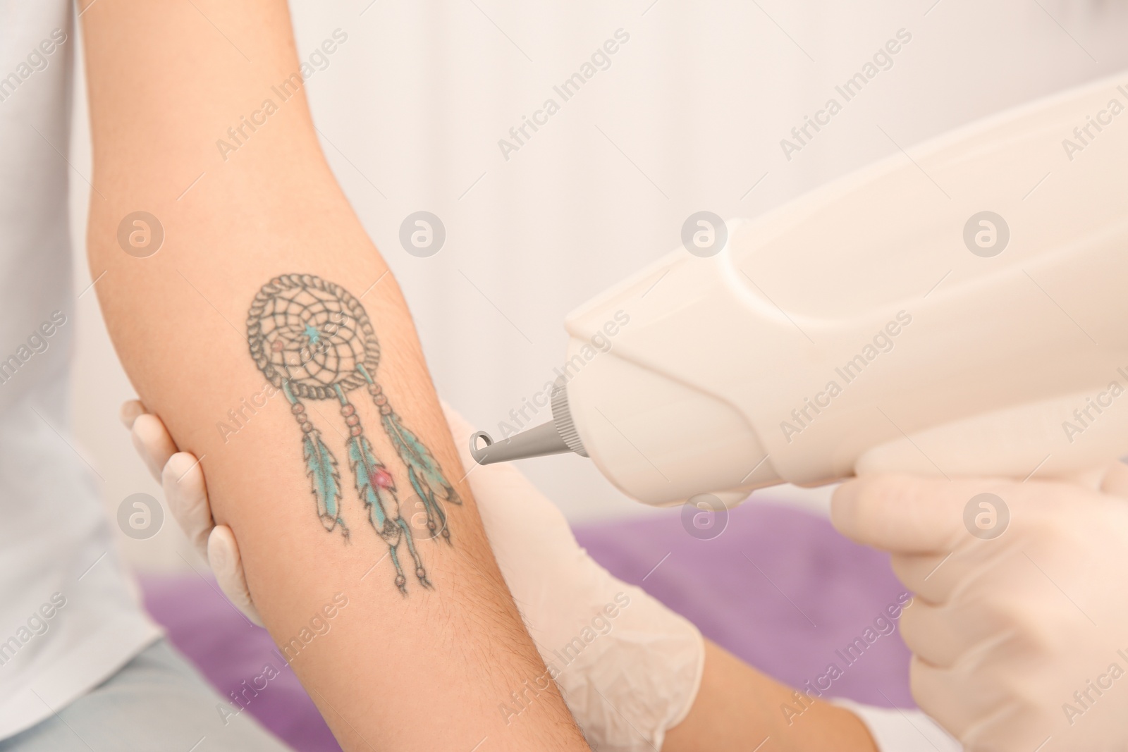 Photo of Young woman undergoing laser tattoo removal procedure in salon, closeup