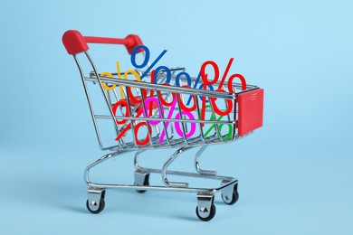 Image of Discount offer. Mini shopping cart with percent signs on light blue background