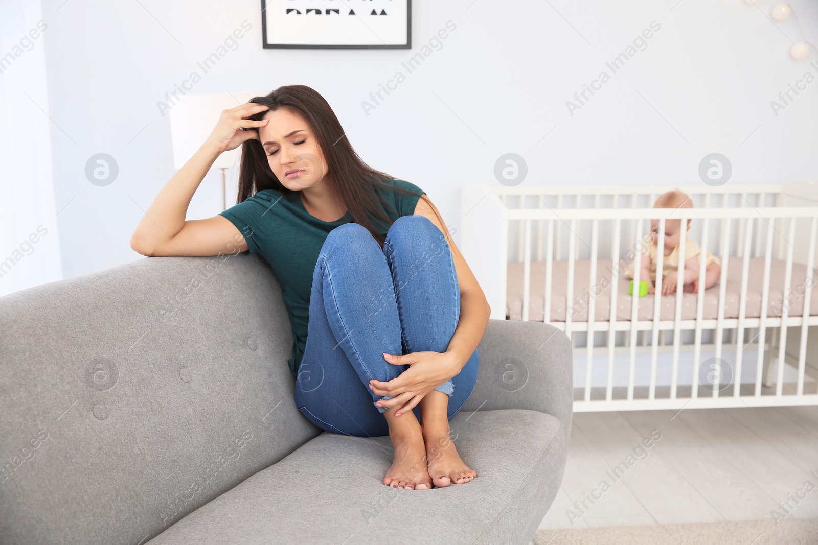 Photo of Young mother suffering from postnatal depression and little baby in room