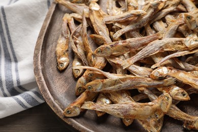 Wooden plate of tasty dried anchovies on table, closeup