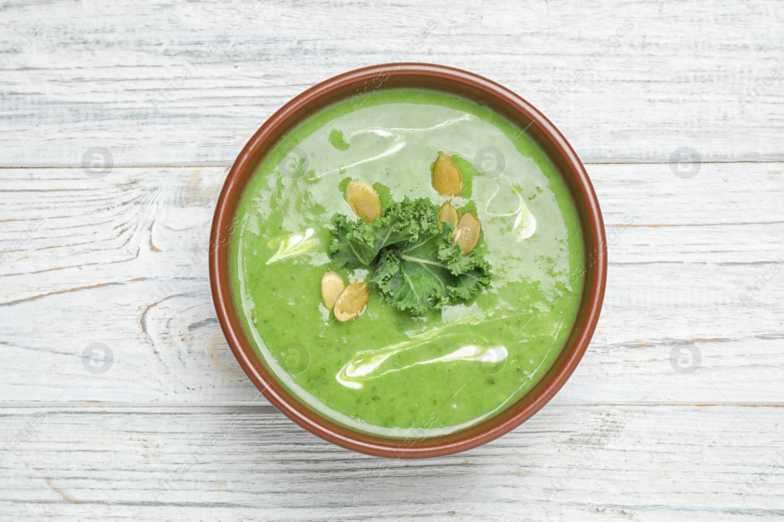 Photo of Tasty kale soup on white wooden table, top view