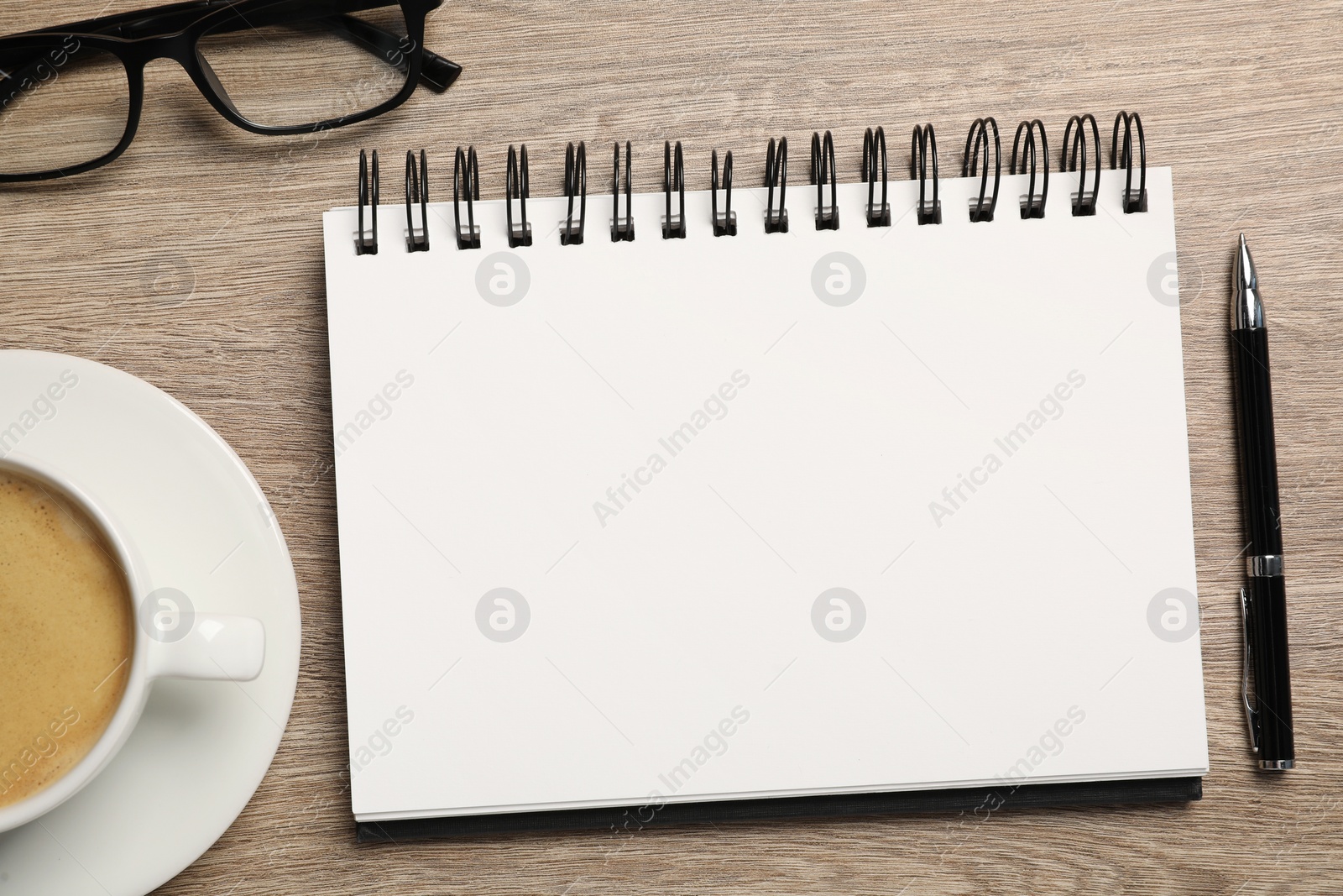 Photo of Empty notebook, coffee, glasses and pen on wooden table, flat lay