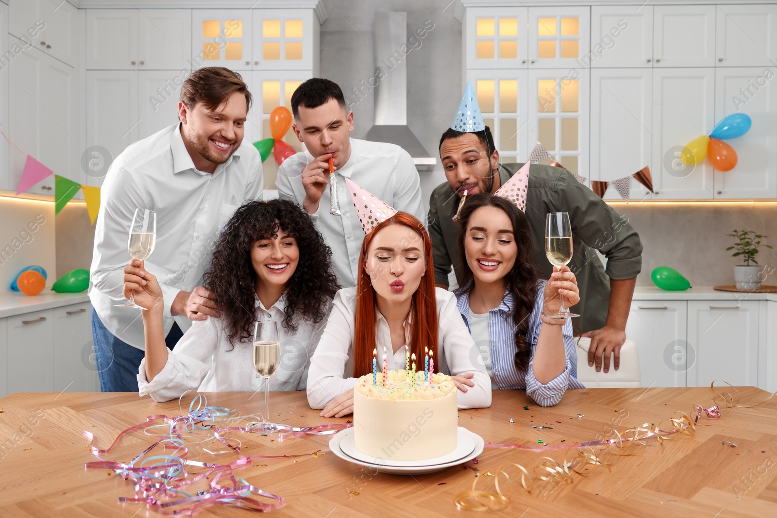 Photo of Happy friends with tasty cake celebrating birthday in kitchen