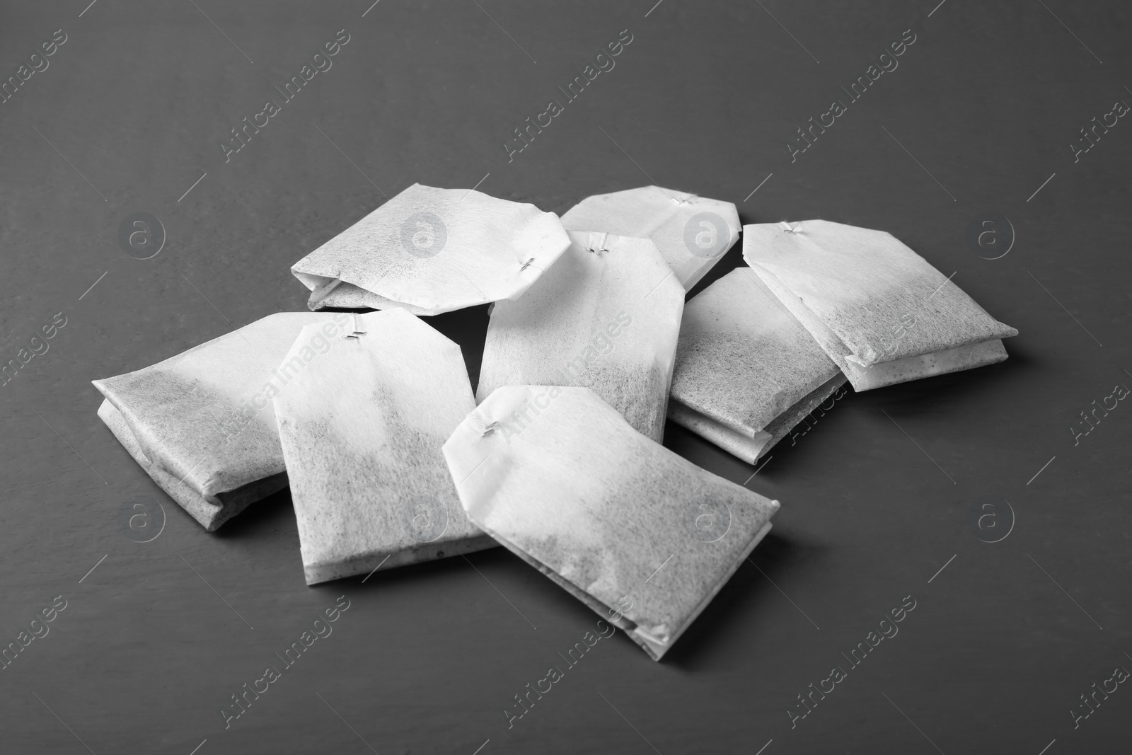 Photo of Many tea bags on grey wooden table, closeup