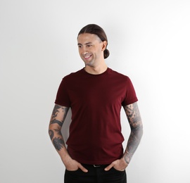 Photo of Young man with stylish tattoos on white background
