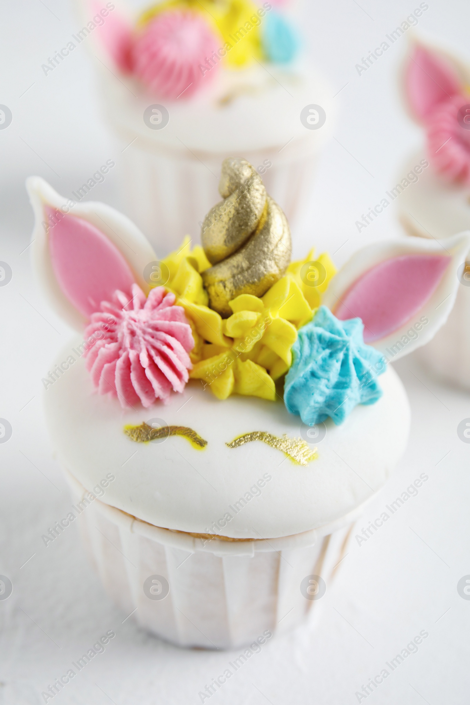 Photo of Cute sweet unicorn cupcake on white table, closeup