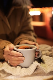 Woman with cup of mulled wine at table, closeup. Space for text