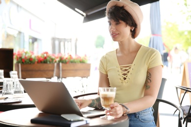 Young woman working with laptop at desk in cafe