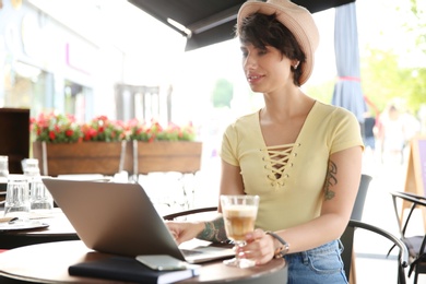 Photo of Young woman working with laptop at desk in cafe