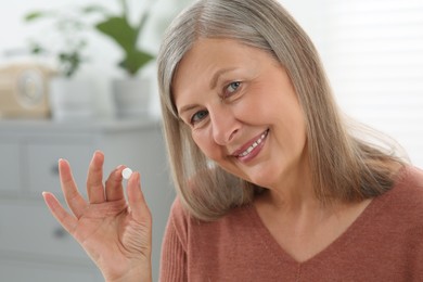 Beautiful senior woman with pill at home