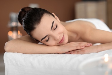 Photo of Young woman lying on massage table in spa salon