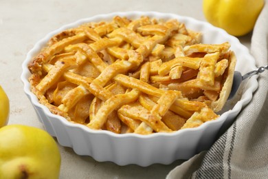 Photo of Tasty homemade quince pie with cake server on light table, closeup