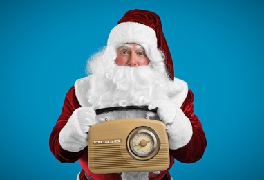 Photo of Santa Claus with vintage radio on blue background. Christmas music