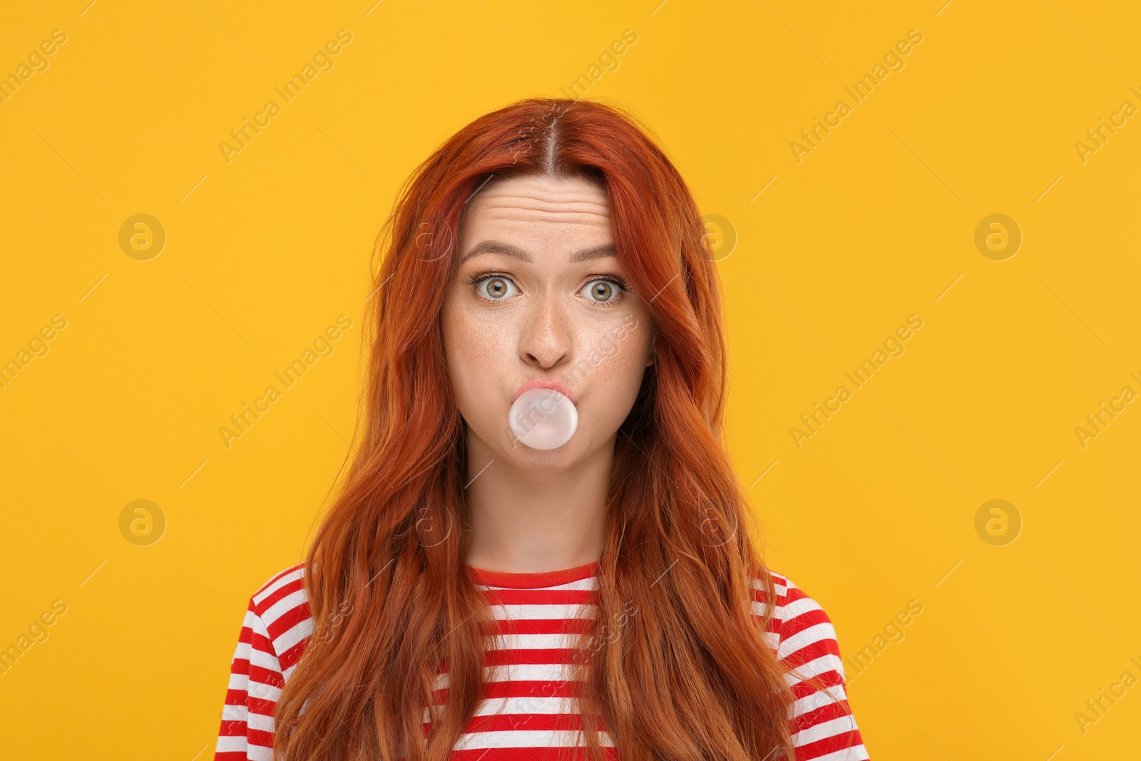 Photo of Portrait of surprised woman blowing bubble gum on orange background