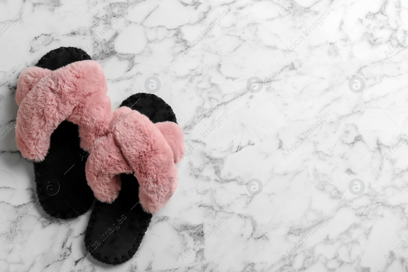 Photo of Pair of soft slippers on white marble background, flat lay. Space for text