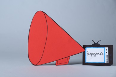 Photo of Propaganda concept. Big paper megaphone and TV on light grey background