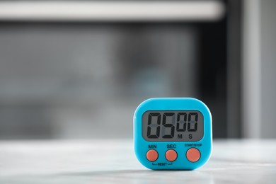 Photo of Kitchen timer on light grey table against blurred background. Space for text