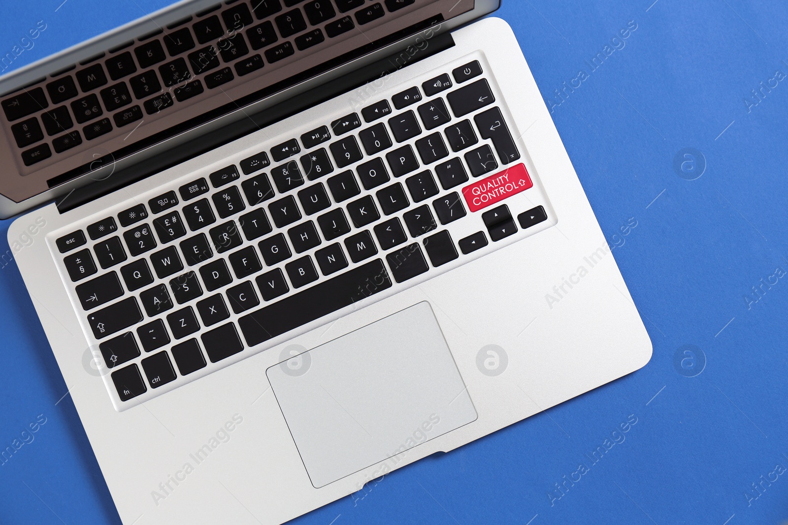 Image of Modern laptop with quality control button on blue background, top view  