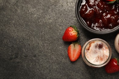 Photo of Tasty yoghurt with jam and strawberries on grey textured table, top view. Space for text