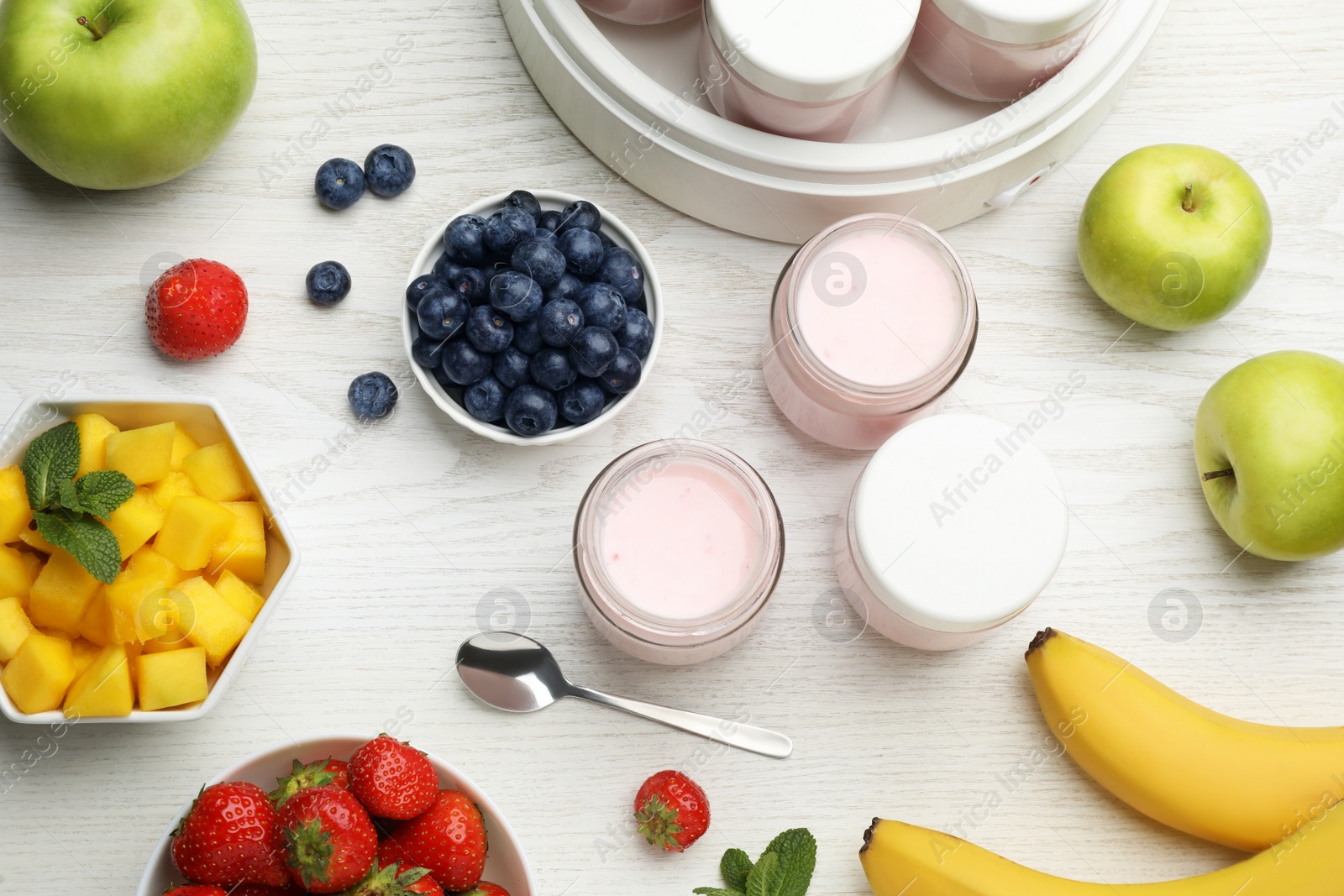 Photo of Jars of fresh yogurt and different fruits on white wooden table, flat lay