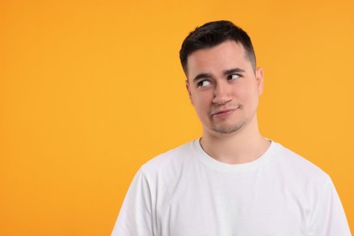 Photo of Portrait of embarrassed young man on orange background, space for text