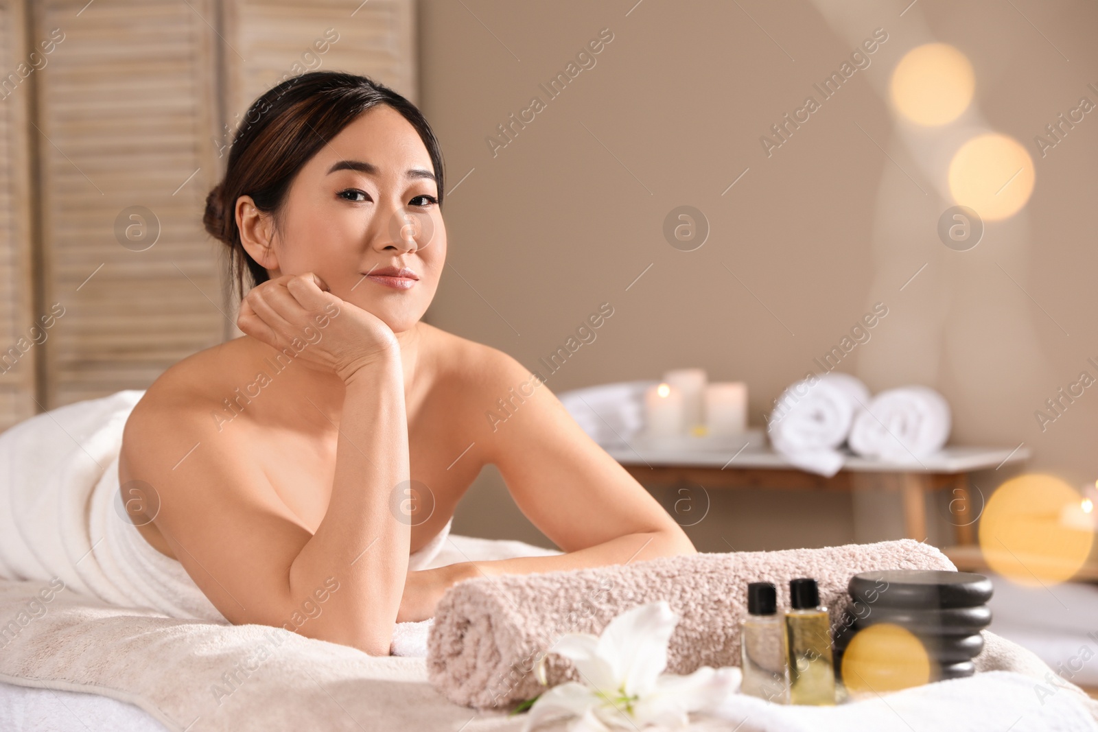 Photo of Beautiful Asian woman lying on massage table in spa salon. Space for text