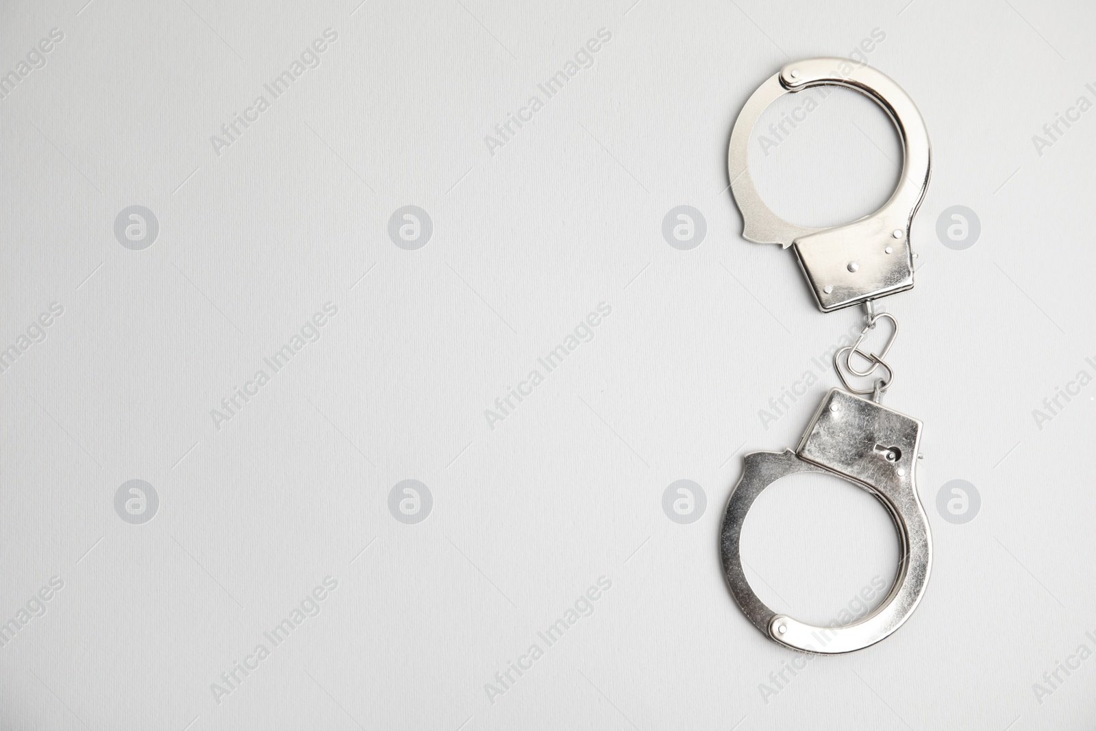 Photo of Classic chain handcuffs on white background, top view. Space for text