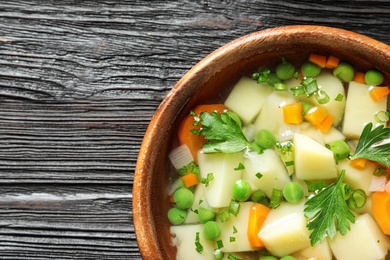 Photo of Bowl of fresh homemade vegetable soup on dark wooden background, top view. Space for text