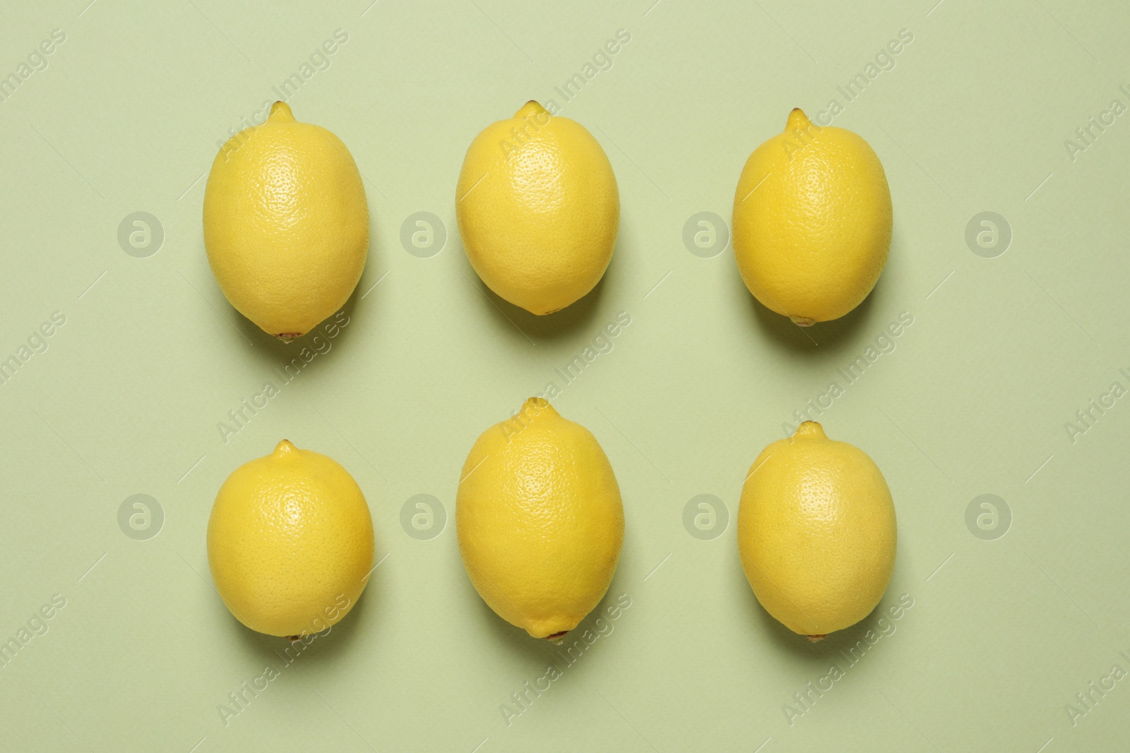 Photo of Fresh ripe lemons on light green background, flat lay