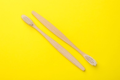 Photo of Bamboo toothbrushes on yellow background, flat lay