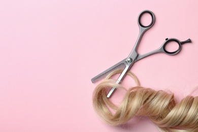 Flat lay composition with strand of blond hair, thinning scissors and space for text on color background. Hairdresser service