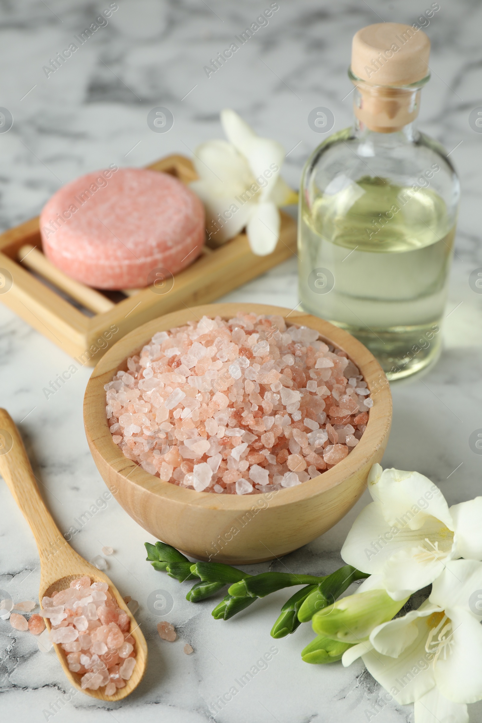 Photo of Beautiful spa composition with sea salt, soap bar, essential oil and flowers on white marble table