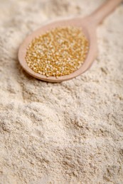 Photo of Spoon with quinoa seeds on flour, closeup