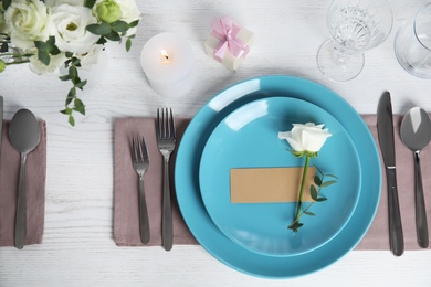 Elegant festive table setting with blank card on white wooden table, flat lay