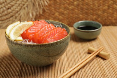 Delicious salmon sashimi served with funchosa and lemon on bamboo mat, closeup
