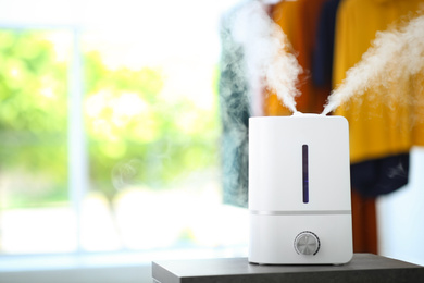 Photo of Modern air humidifier on table indoors. Space for text