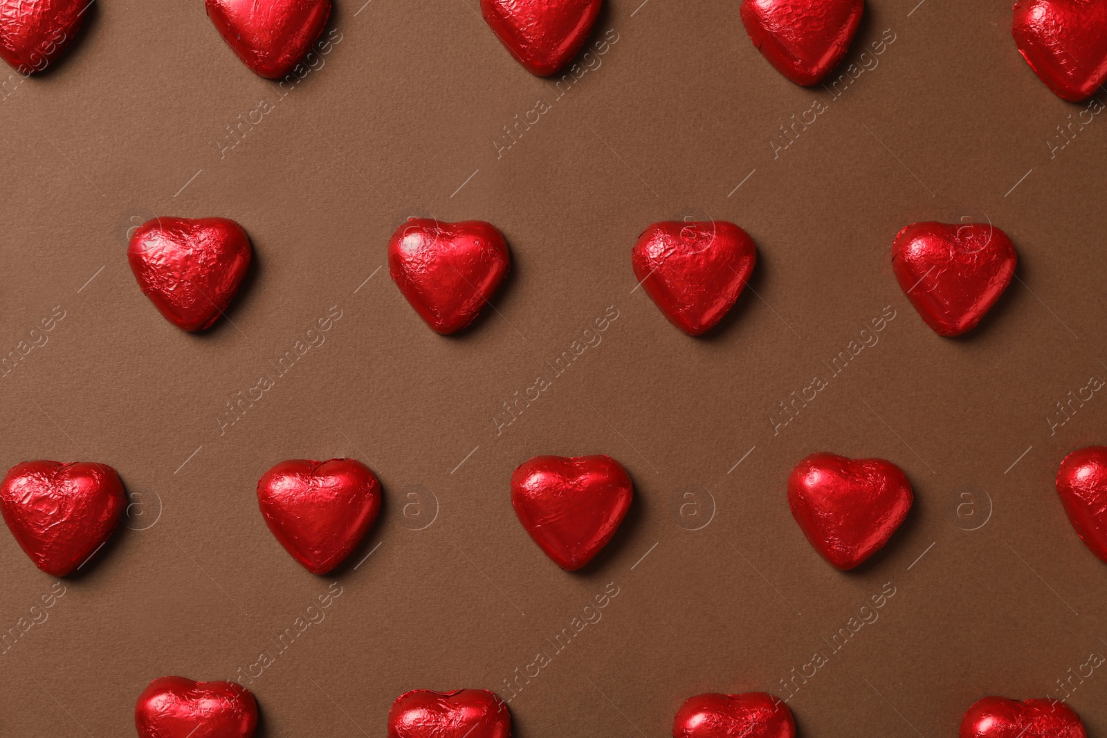 Photo of Tasty chocolate heart shaped candies on brown background, flat lay